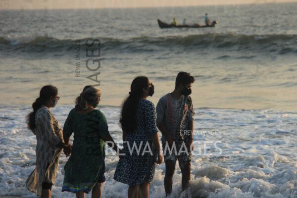 A family having fun at a Puthuvype beach in Kochi, Kerala during sunset, as they step into the waves.